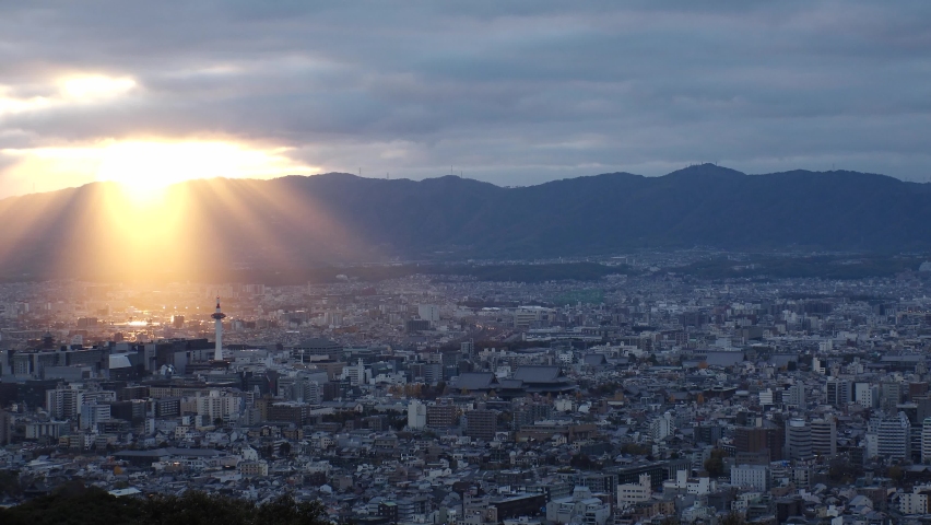 KYOTO, JAPAN - DEC 2021 : Aerial high angle sunset view of Kyoto city. Scenery of mountain, streets and buildings around downtown central area. Japanese nature and traditional old town concept video.