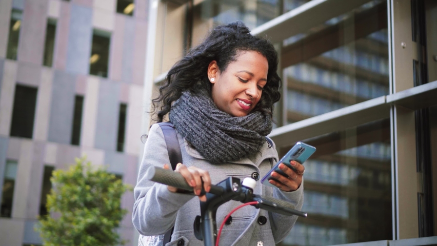 Happy smiling girl walking and texting with mobile phone using message app. Young latin woman going to the job reading news on cellphone. High quality 4k footage | Shutterstock HD Video #1097279957