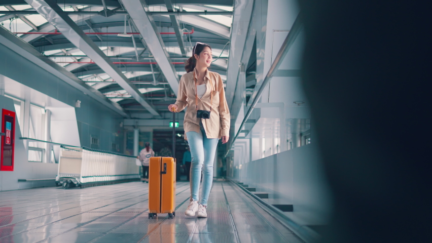Happiness smiling asian woman passenger walking with a yellow suitcase luggage at airport terminal, Woman on way to flight boarding gate, Tourist journey trip concept