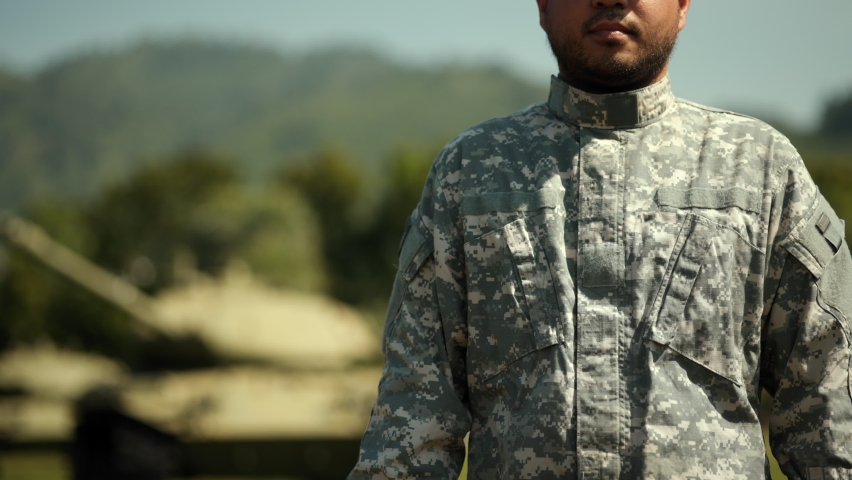 Confident soldier man in military uniform special forces  standing against on field Mission. Commander Army soldier military defender of nation in uniform standing near battle tank while state of war.