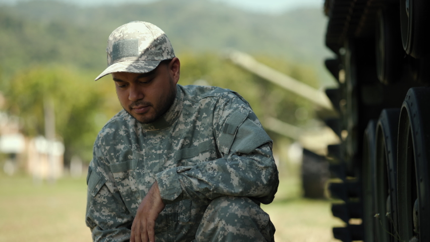 Happy man in military uniform special forces soldier standing against on field Mission. Commander Army soldier military defender of nation in uniform standing near battle tank while state of war.