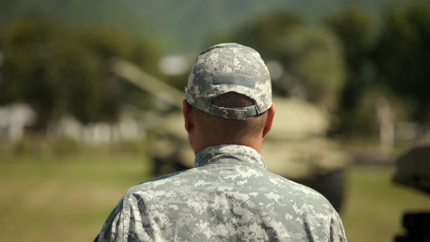 Soldier man in military uniform special forces saluting standing against on field Mission. Commander Army soldier military defender of  nation in uniform standing near battle tank while state of war.