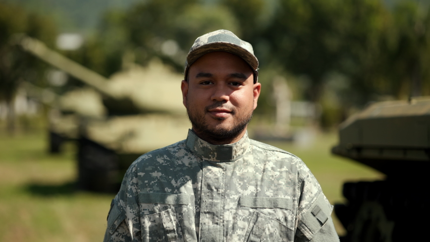 Happy soldier man in military uniform special forces standing against on field Mission. Commander Army soldier military defender of nation in uniform standing near battle tank while state of war.