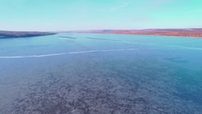 Frozen European lake, on which people prepare for fishing. Drone video. 4K.
