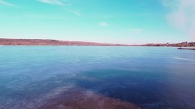 European lake, located near a city, covered with a thin layer of ice, during the winter. Drone video. 4K.