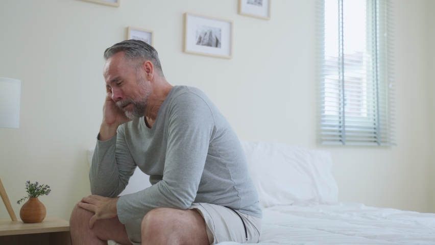 Caucasian senior older depressed man sitting alone in bedroom at home. Attractive elderly mature male feeling sad, lonely and frustrated with life problem think of money debt, budget loss, bankruptcy. | Shutterstock HD Video #1097284707