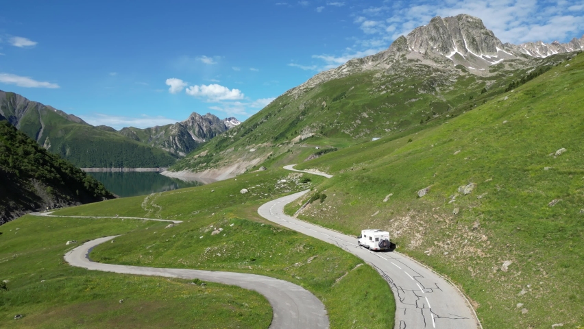 RV Motorhome drives along Mountain Lake Lac de Grand Maison in French Alps - Aerial Follow