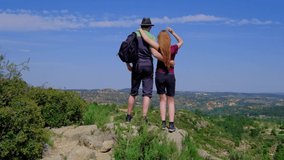 Man and woman standing and hugging. Happy couple. Hiking in nature. Beautiful landscape from a cliff. Concept of freedom and happiness. Horizontal video in a slow motion.