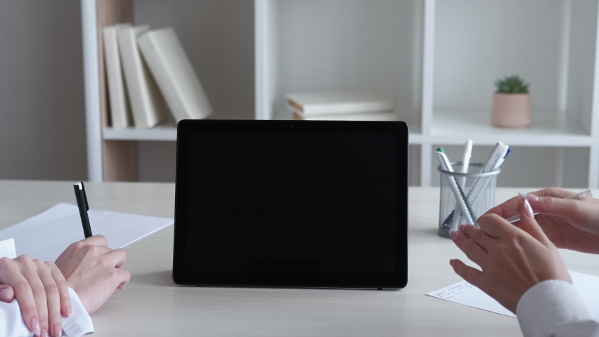Video conference. Virtual meeting. Online communication. Unrecognizable female business colleagues discussing work with hands at workplace with black mockup screen tablet. | Shutterstock HD Video #1097289747