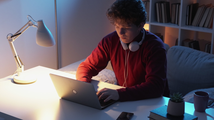 Distance work. Displeased man. Online communication. Casual pensive guy typing laptop sitting desk light shadow home interior. | Shutterstock HD Video #1097289821