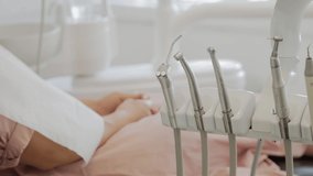 Dental instruments and a woman in a pink dress in the dentist's chair in the background. Without a face. Background for a dental video. High quality 4k footage