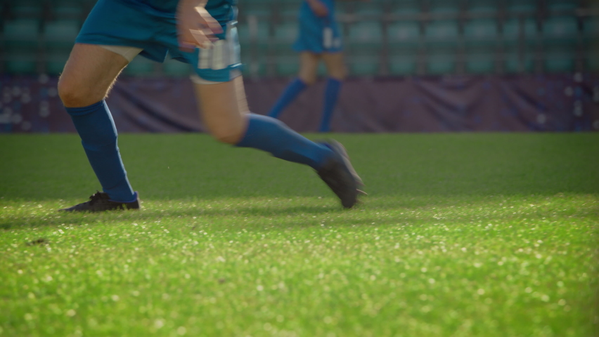 Soccer Match Stadium Blue Team Football Player Trying to Tackle Ball, but failing. Dangerous Moment in the Game. Professional Tournament Cup in Action