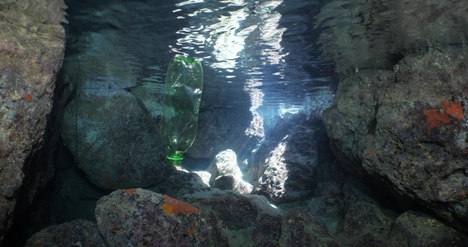 A green plastic bottle in a cave underwater ocean pollution with sun beams and rays | Shutterstock HD Video #1097292167