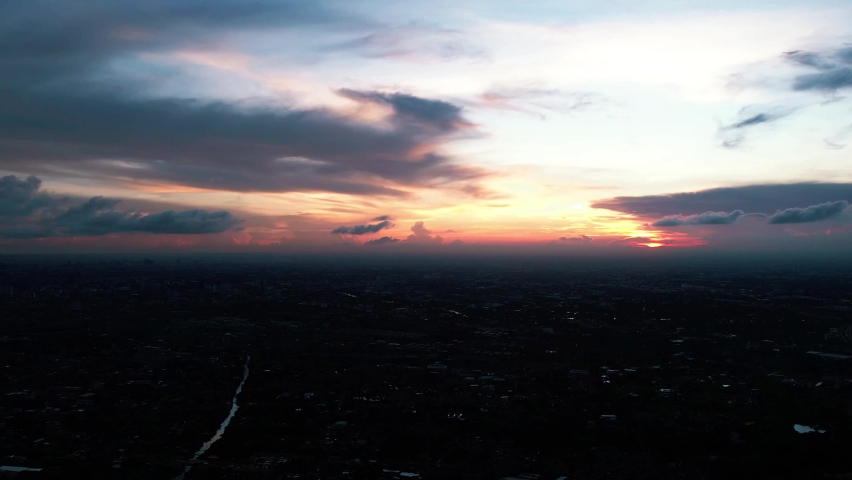 Beautiful sunset on coastline tropical beach with golden sea and silhouette travel people on nature background, Ocean sunset timelapse, fly in clouds, sun going beyond the horizon illuminating water