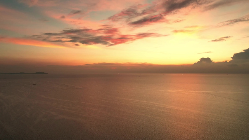 Beautiful sunset on coastline tropical beach with golden sea and silhouette travel people on nature background, Ocean sunset timelapse, fly in clouds, sun going beyond the horizon illuminating water