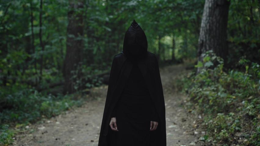 A terrible black figure without a face in a mystical forest. The horror of forest paths. Royalty-Free Stock Footage #1097294439