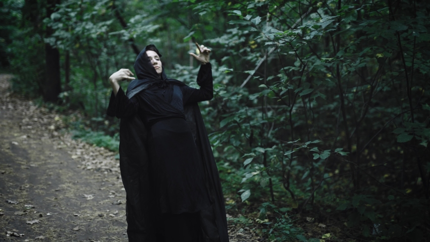 Medieval witch moving along a forest path. Strange convulsions in the woman's movement | Shutterstock HD Video #1097294445