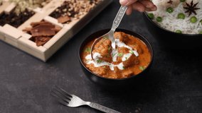 Butter chicken Indian woman hand serving eating roti and Murgh Makhani curry. Popular tikka masala chicken curry in Punjabi Dhaba India. North Indian non vegetarian cuisine 