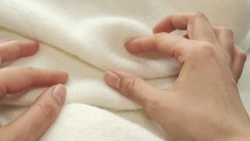 female's hand on the fabric of white plush cloth with soft nap. Clothing industry concept, slow motion. woman checking the quality of clothes, enjoys the soft pleasant texture of the fabric Royalty-Free Stock Footage #1097295533