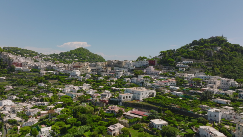 Aerial panoramic footage of houses in urban borough. Buildings with green gardens in slope. Capri, Campania, Italy