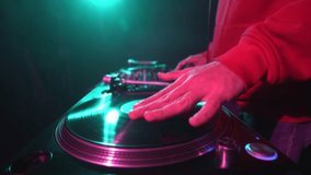 Hip hop DJ scratches vinyl record on turntable. Club disc jocket playing music on party