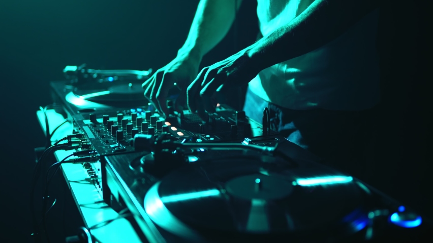 Techno party DJ mixing music with sound mixer and turntables. Hip hop disc jockey plays set on party in night club Royalty-Free Stock Footage #1097299107