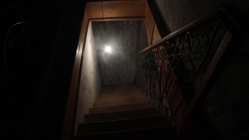 Creepy wooden stairs going down to the Basement in an abandoned house. Swinging bulb. Horror Halloween concept. Gimbal Steady cam shot Royalty-Free Stock Footage #1097306563