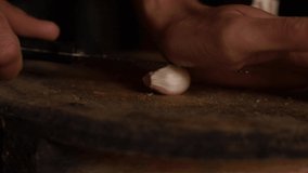Horizontal video of a garlic crushed by a knife on a board. Food.