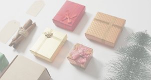 Animation of christmas greetings text over christmas presents and decorations. Christmas, festivity, celebration and tradition concept digitally generated video.