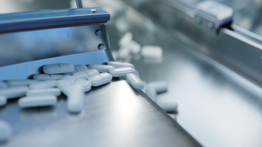 Tablets and Capsules Manufacturing Process. Macro Shot of Medicinal Drug Production. White Painkiller Pills are Moving on Conveyor at Modern Pharmaceutical Factory. 