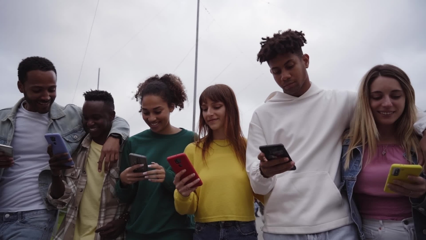 Low angle view of a group of young teenagers friends using cell phones and walking in the city. Concept of community millennial people addicted to technology. Social Media communication generation Z | Shutterstock HD Video #1097326805