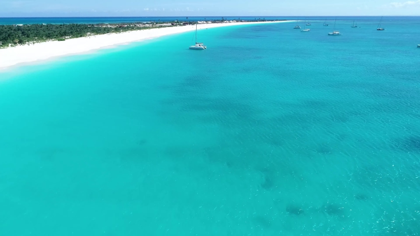The catamaran sails along the shore. White catamaran floats in turquoise colored water close to white sandy coastline. Drone point of view. Camera flies close to the surface of the water. Royalty-Free Stock Footage #1097327639