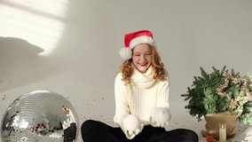 Girl with red curly hair and Santa hat plays or juggles with Christmas balls on white background. Merry Christmas concept. High quality FullHD footage with slow motion - Powered by Shutterstock - Get 15% off with code: PIKWIZARD15