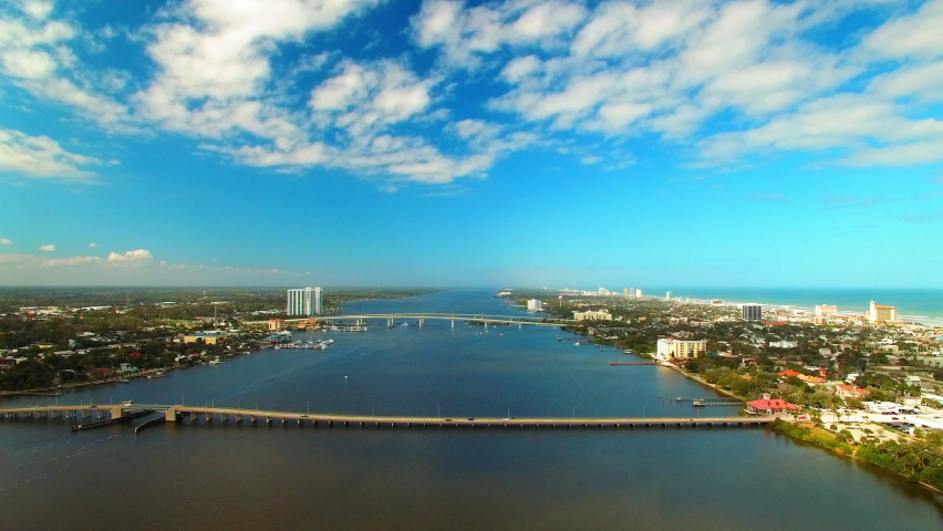 Aerial Backward Shot Of City With Bridges Over Sea In City Under Cloudy Sky - Daytona Beach, Florida