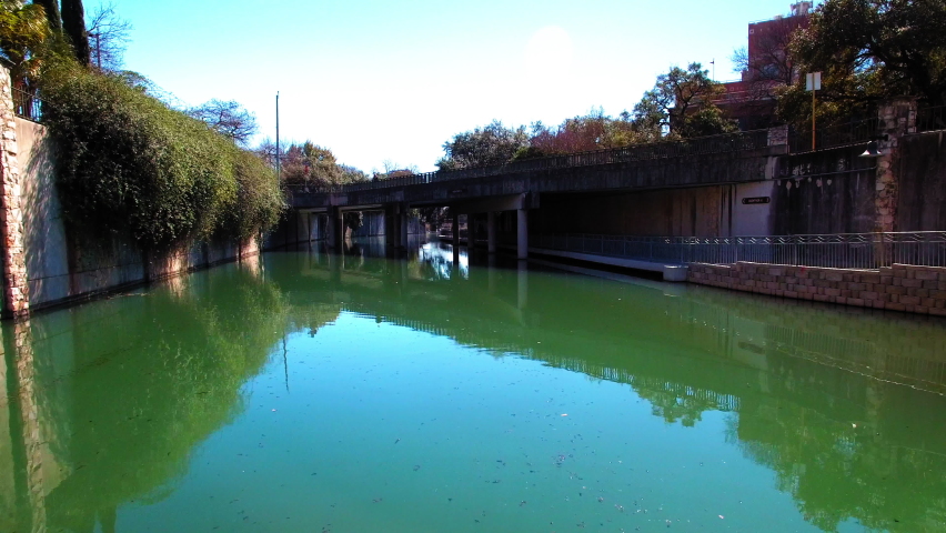 Woman On Bridge Looking At San Antonio River In City Against Clear Sky