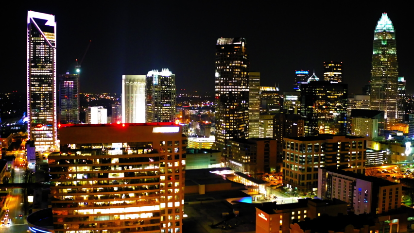 Aerial Shot Of Sparkling Modern Office Buildings In Downtown Against Clear Sky, Drone Flying Backwards Over City At Night - Charlotte, North Carolina