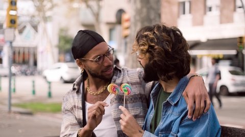 Gay couple eating a lollipop while chatting in the street Stockvideo