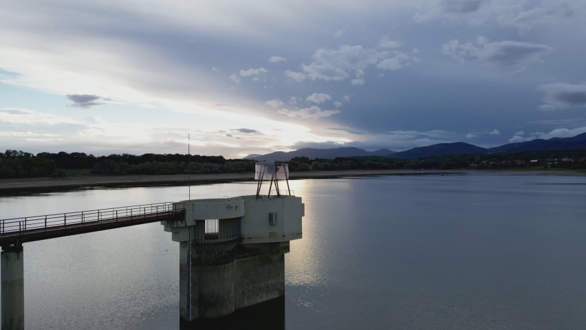Water intake tower of the Michelbach lake dam (Upper-Rhine, Alsace, France), in drought weather in summer, with a very low water level, at sunset, with the mountains in the background, upwards move