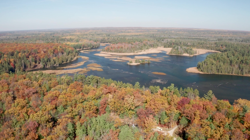 Au Sable River in Michigan with fall colors and drone video moving over trees.