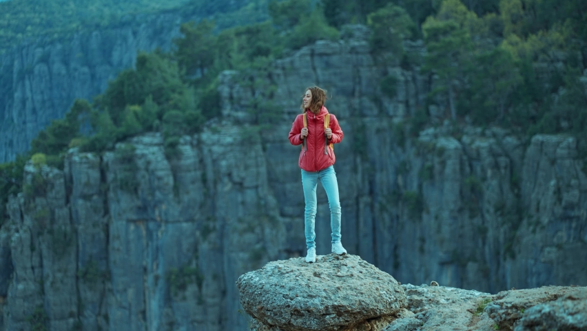 tourist hiker girl in red jacket with backpack walks on edge cliff and overlooking big canyon, panoramic view. Tazi Canyon is common tourist destination in Turkey