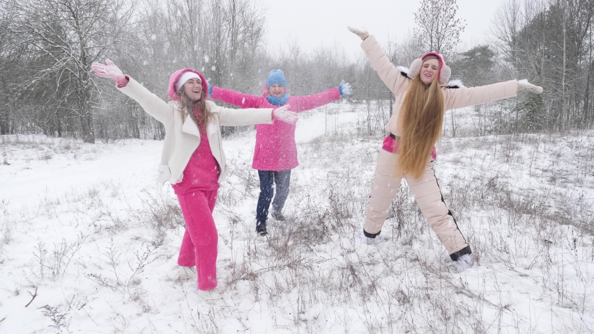 Three cheerful women in warm clothes laugh and throw up snow in snowy nature | Shutterstock HD Video #1097351277