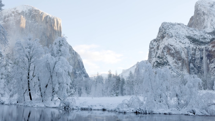 Fresh snow along the Merced River in Yosemite National Park, California. El Capitan can be seen on the left. Royalty-Free Stock Footage #1097354673
