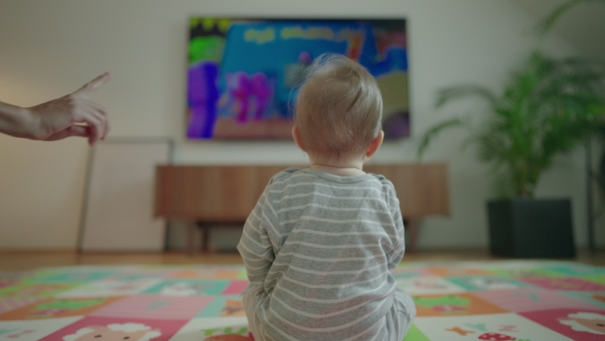 Slow motion - Little baby watching TV on the floor, parent shows a "no-no" sign and turns off the television. Baby is confused Royalty-Free Stock Footage #1097354781
