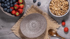 Stop motion animation of yogurt with granola and berries. Eating greek yogurt with crunchy oat honey granola, blueberries, strawberries. Healthy food, healthy breakfast concept