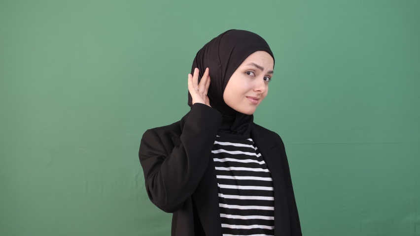 Muslim girl hearing loss in front of green screen, female try to listen , hijab girl is expression curiously, chroma key | Shutterstock HD Video #1097357335