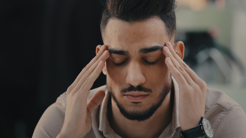 Portrait close up sad upset sick unhappy man unhealthy guy businessman has problem trouble massaging temples suffer headache depressed Hispanic Indian male suffering from migraine difficult job loss | Shutterstock HD Video #1097360693