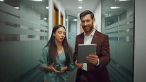 Smart people going through office closeup. Creative digital devices colleagues talking in modern corridor closeup. Busy man woman working next to glass wall meeting room indoors. Teamwork concept  - Powered by Shutterstock - Get 15% off with code: PIKWIZARD15