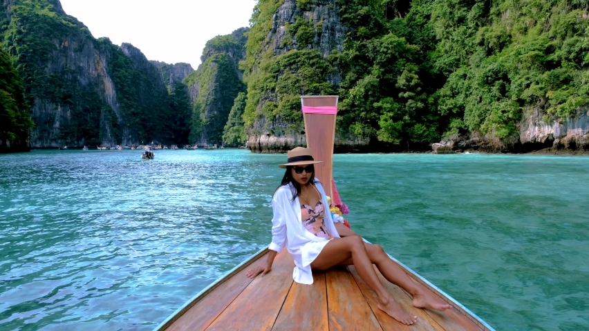 Pileh Lagoon with the green emerald ocean at Koh Phi Phi Thailand, women with hat in front of longtail boat | Shutterstock HD Video #1097364605