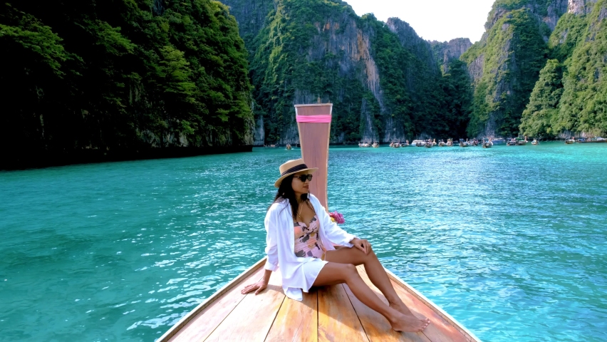Thai women in front of longtail boat at Pileh Lagoon with the green emerald ocean at Koh Phi Phi Thailand,  | Shutterstock HD Video #1097364611