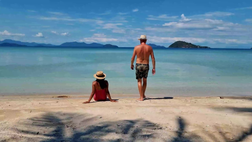 A Couple of men and women with a hat relaxing on the beach of Koh Mak Thailand, the tropical beach with a couple of men and women on the beach | Shutterstock HD Video #1097364635